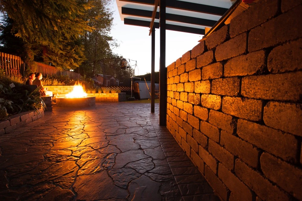 Retaining wall on stone patio next to a bonfire in a fire pit