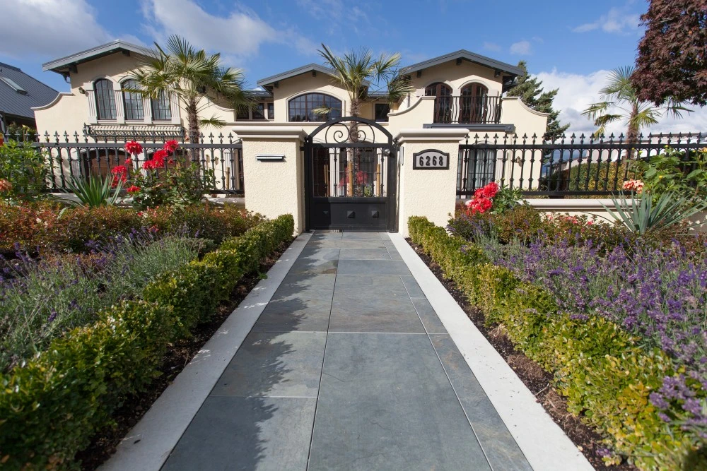 residential-paving-stones Paving stone path lined with flowers leading to gated home