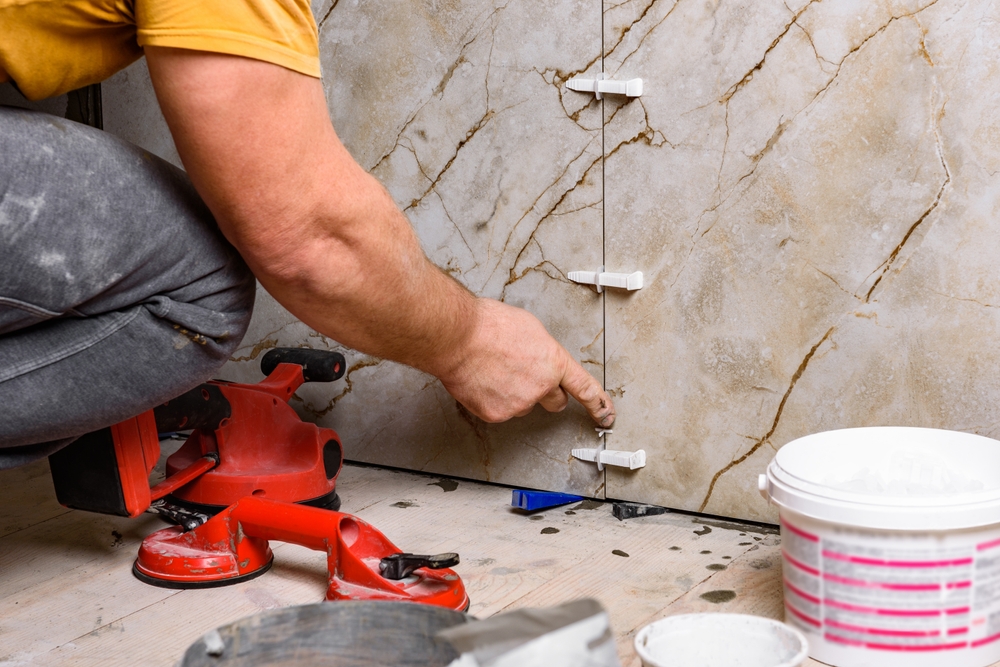 Installer setting marble-look porcelain wall tiles with leveling clips during an installation in Vancouver