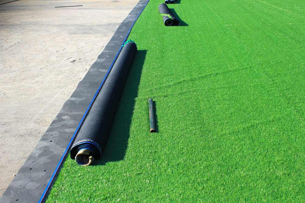 Artificial,Turf,Soccer,Field,Construction Roll of artificial turf being unrolled over a prepared base during a professional turf installation in Vancouver