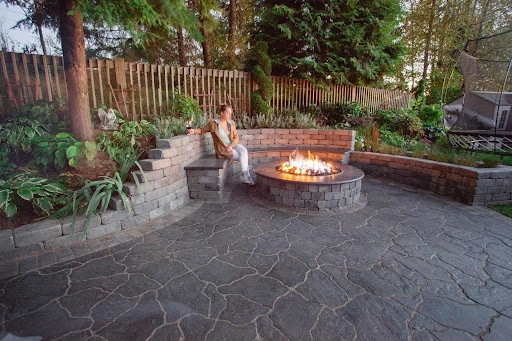 fire-pit-construction-vancouver Woman sitting on a bench with a glass of wine in front of a fire pit